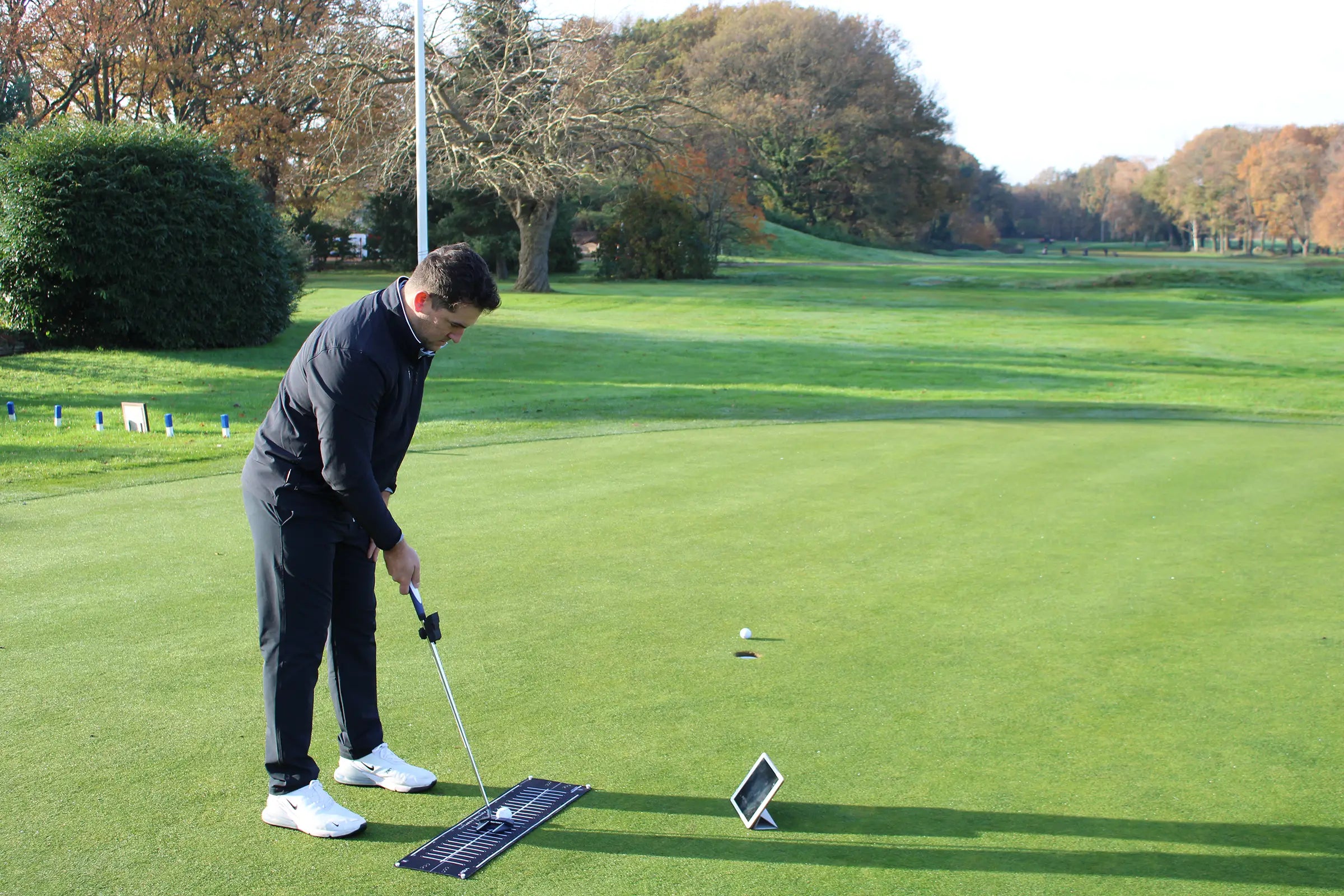 A golfer using the Capto Golf putting analysis system on a green. The player is practicing with a Gen 3 putter, alignment mat, and tablet for real-time feedback and performance tracking.