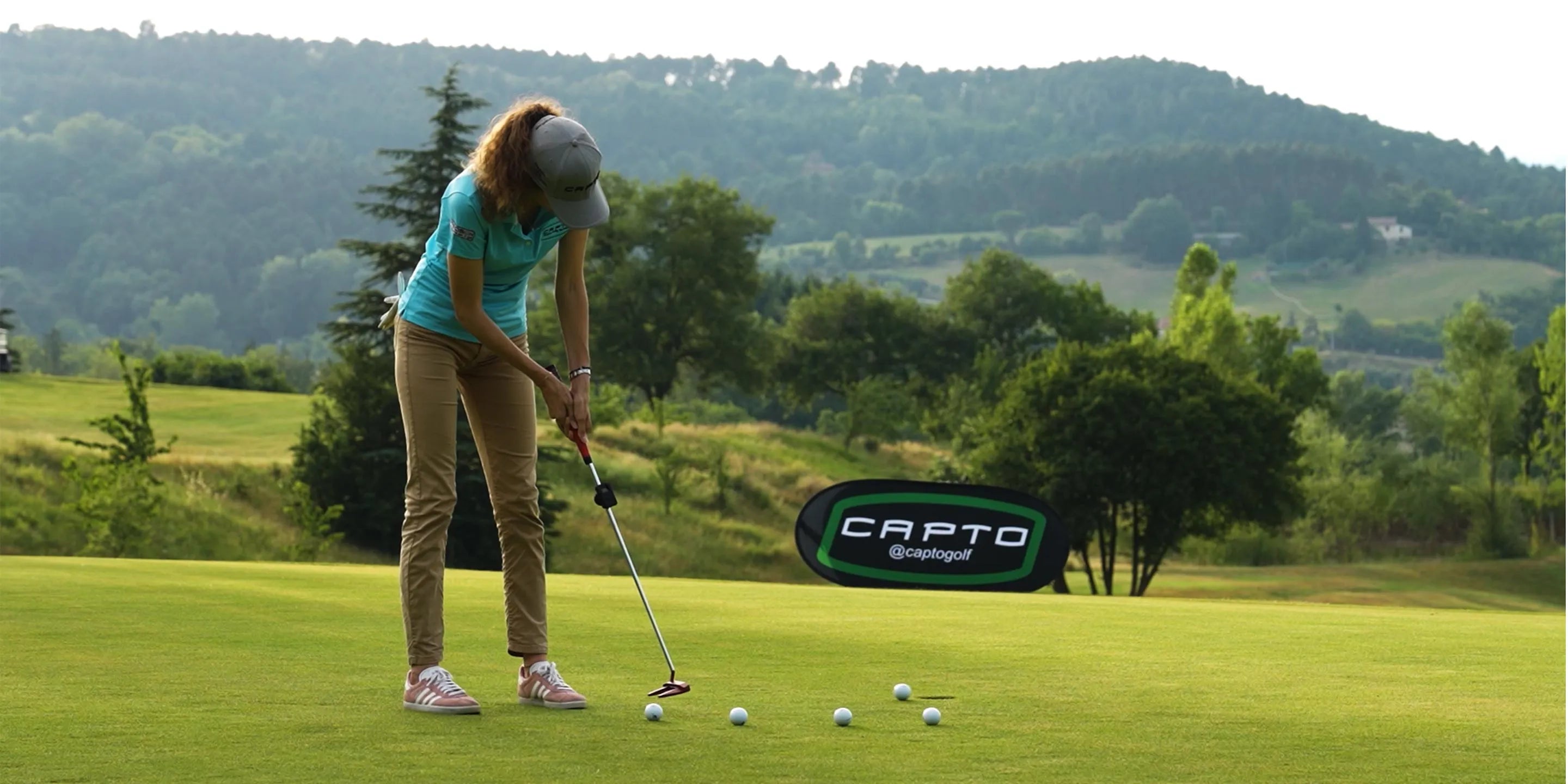 A golfer putting out on a green using the Capto device