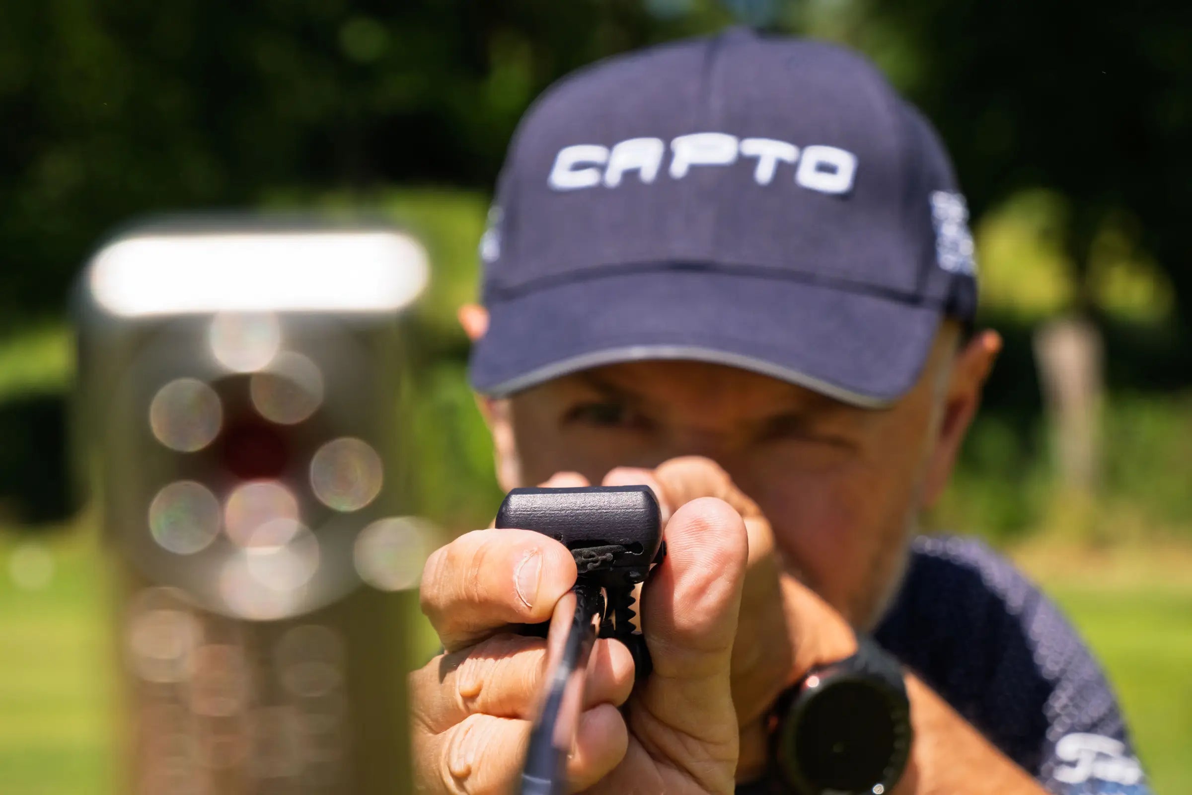 Capto Golf coach checking a putter-mounted sensor to measure club face angle, alignment and putting stroke accuracy during performance analysis.