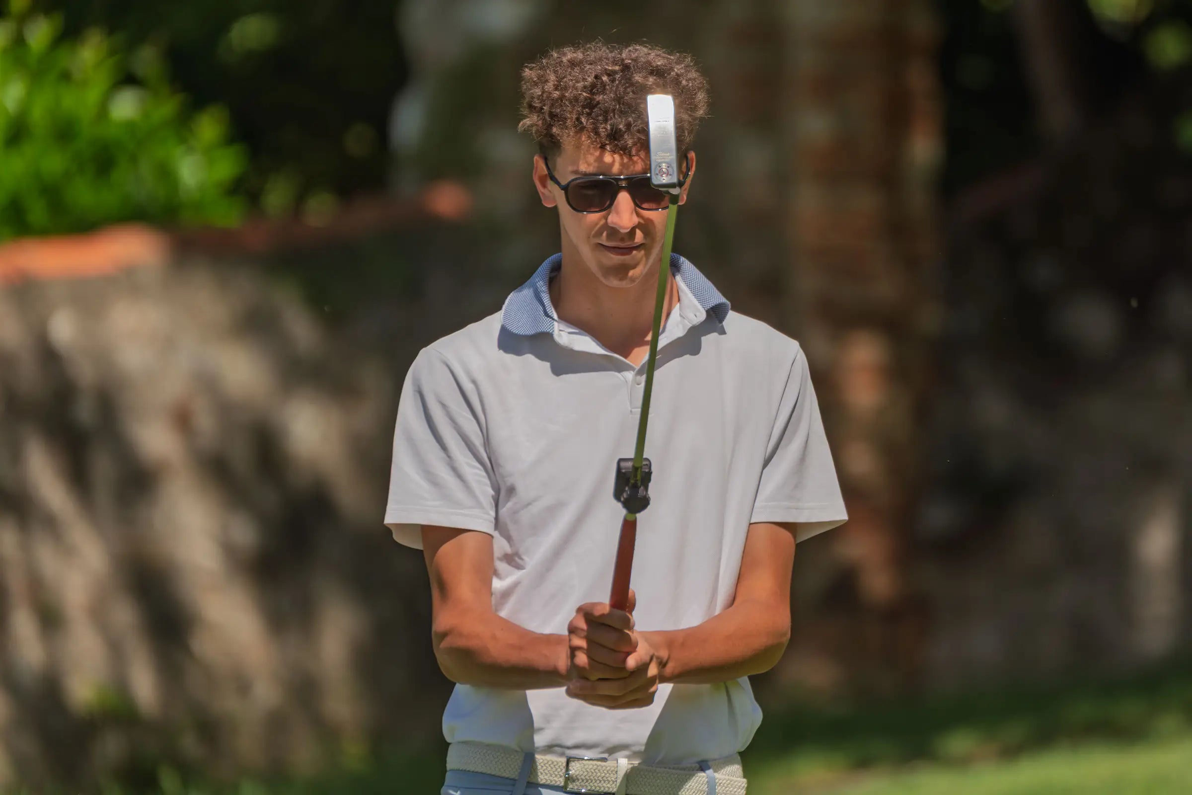 Golfer using a Capto Golf putting sensor to analyse putter alignment, face angle and stroke consistency during putting practice.